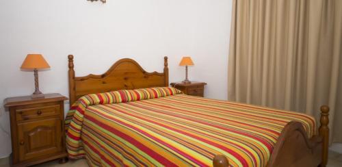 a bedroom with a bed with a colorful striped blanket at Apartamento Bajo en el Tamaduste Zona Privilegiada in Tamaduste