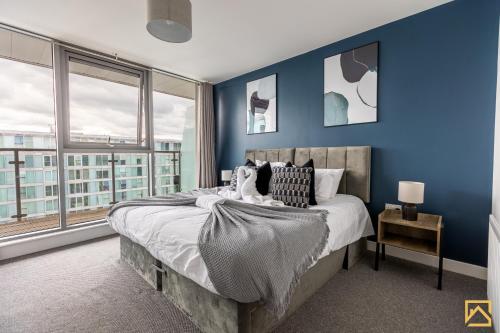 a bedroom with blue walls and a bed with pillows at Luxury 2-bed In central MK By Valore Property Services in Milton Keynes