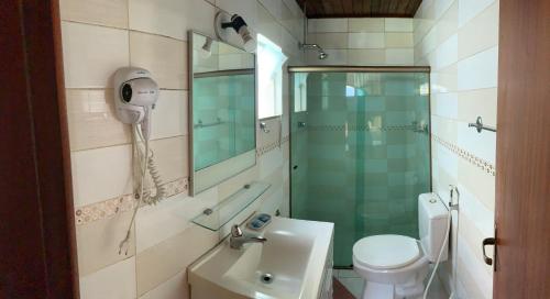 uma casa de banho com um chuveiro, um WC e um lavatório. em Bougainville Suítes em Arraial do Cabo
