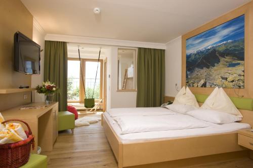 ツェル・アム・ゼーにあるファミロテル アミアモのベッドとテレビが備わるホテルルームです。