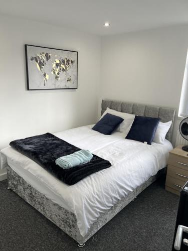 een slaapkamer met een bed met witte lakens en blauwe kussens bij Deluxe En-Suite Bedroom In the Centre of Watford in Watford