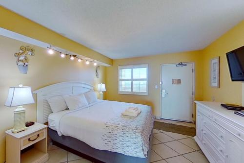 a bedroom with a white bed and a tv at Camelot by the Sea 1804 in Myrtle Beach