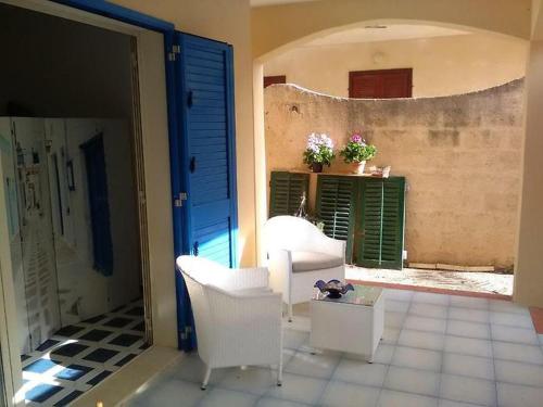 een woonkamer met witte stoelen en een blauwe deur bij Brezza di mare in Punta Secca