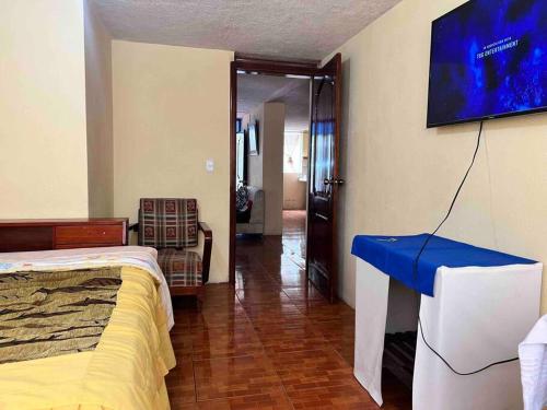 um quarto com uma cama e uma televisão na parede em Ventana al Pedacito de Cielo em Baños