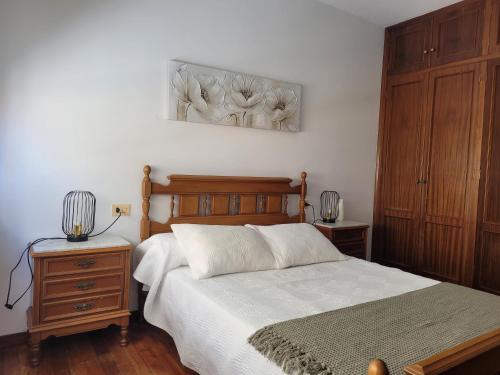 a bedroom with a bed with a wooden headboard and wooden cabinets at PIso de 3 habitaciones en centro de Miño in Miño