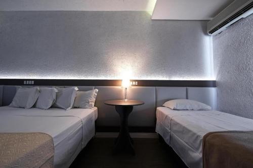 una camera con due letti e un tavolo con una lampada di Dall’Onder Grande Hotel Bento Gonçalves a Bento Gonçalves