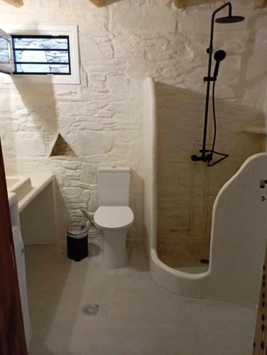 a white bathroom with a toilet and a bath tub at Villa Art Natalie in Kithnos