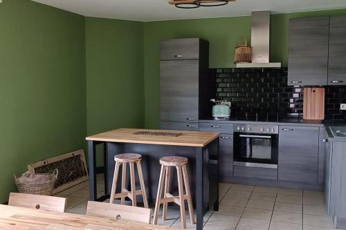 a kitchen with green walls and a wooden island with stools at Les roses d'Olga 