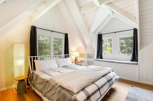 a white bedroom with a bed and two windows at Bayleaf Cottage in Madrona Beach