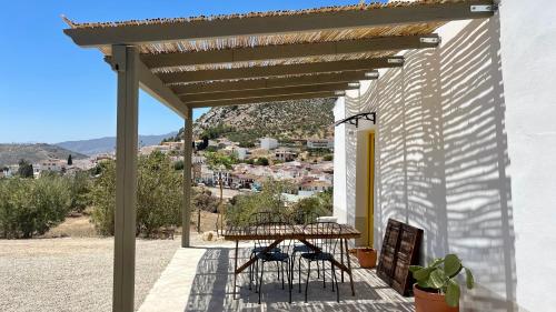 een patio met een tafel en stoelen onder een pergola bij Casita Malacitano, Caminito del Rey in Valle de Abdalagís