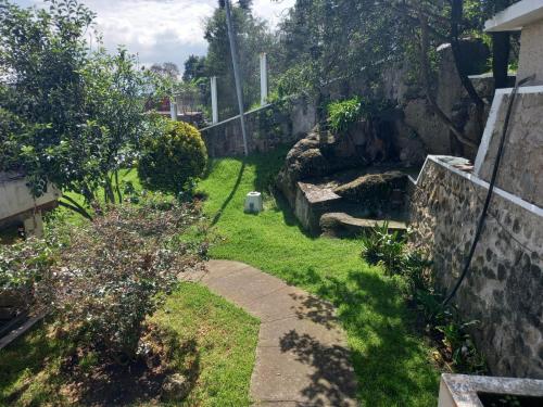 a garden with a stone fence and a path at Hotel y Bungalows Santa Ana in Quetzaltenango