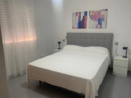 ein weißes Schlafzimmer mit einem weißen Bett und einem Fenster in der Unterkunft Apartamentos Turísticos Magallanes I in San Pedro del Pinatar