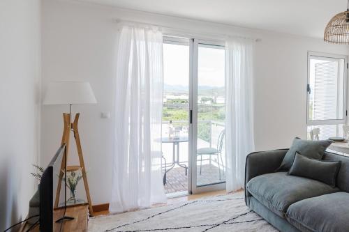 a living room with a couch and a large window at Belavista Oceanside in Ribeira Grande
