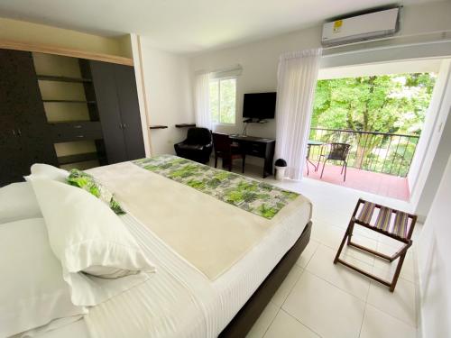 a bedroom with a large bed and a balcony at Hotel Campestre Santa Monica Pance in Cali