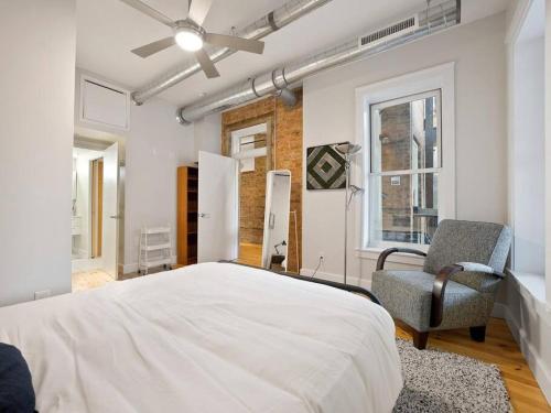 een slaapkamer met een bed, een stoel en een raam bij Findlay Suites Explore OTR with an Outdoor Deck in Cincinnati