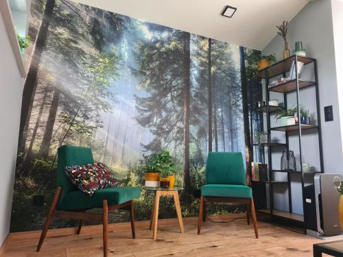 a room with two chairs and a wall mural of a forest at Złota Widokówka in Jaworze