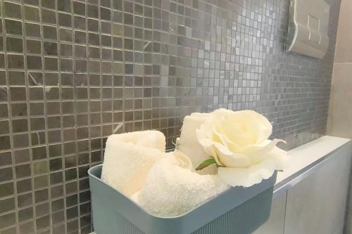 Una cesta de toallas y una flor en el baño. en Elegant house en Pietraperzia