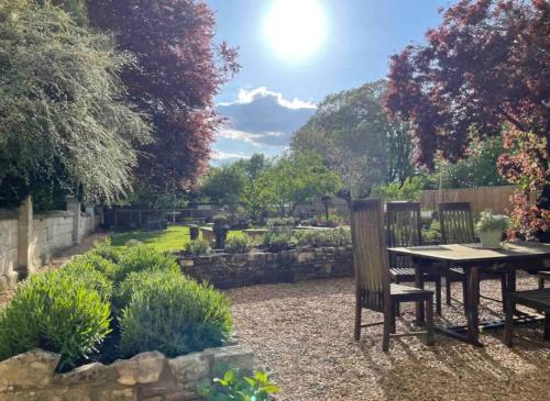 a garden with a table and chairs in the middle of it at Spacious Country Cottage Sleeps 7 Near Bath Fire Pit Dog Friendly in Bradford on Avon