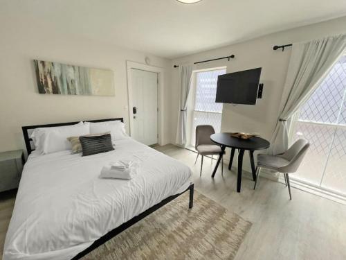 a white bedroom with a bed and a table and chairs at Cute Microapartment Walkable to Everything in Cincinnati