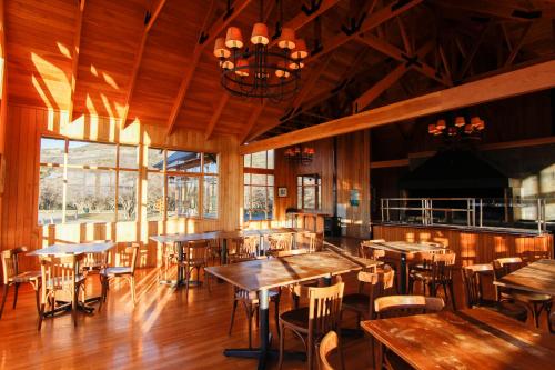 a restaurant with wooden tables and chairs and a chandelier at Glamping Río Serrano - Caja Los Andes in Puerto Natales