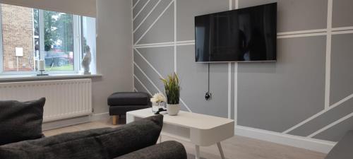 a living room with a couch and a tv on a wall at Ricoh Arena/Newly Refurbished Semi-Detached House in Coventry