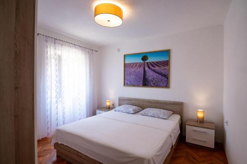 a bedroom with a white bed and a window at Apartments Kaja in Postira