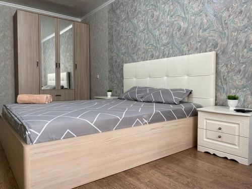 1 dormitorio con 1 cama grande y cabecero grande en 1 ком квартира в районе City center, en Uralsk