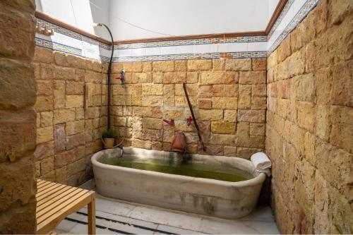 a bath tub in a bathroom with a stone wall at Hotel Balneario de Chiclana in Chiclana de la Frontera