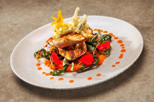 a plate of food with meat and vegetables on a table at Mauna Kea Beach Hotel, Autograph Collection in Hapuna Beach