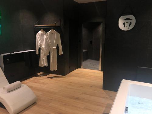 a black room with a white robe and a chair at Appart-hôtel de standing avec jacuzzi privatisable en option in Périgueux