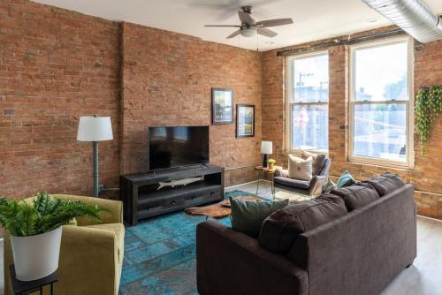 uma sala de estar com paredes de tijolos, sofás e uma televisão em TRUTH Old world charm meets New world love em Cincinnati