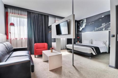 a hotel room with a bed and a couch at Hôtel des Lumières Lyon Meyzieu Arena Stadium in Meyzieu