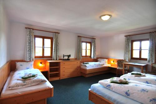 a bedroom with two beds and a desk and windows at Pferdehof Oberegg in Werfenweng