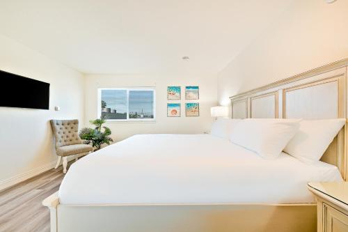a white bedroom with a large white bed and a chair at Sunshine Fun Time in Newport Beach