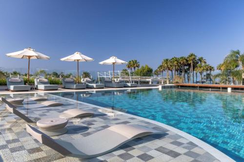 a swimming pool with chairs and umbrellas at a resort at Parklane, a Luxury Collection Resort & Spa, Limassol in Limassol