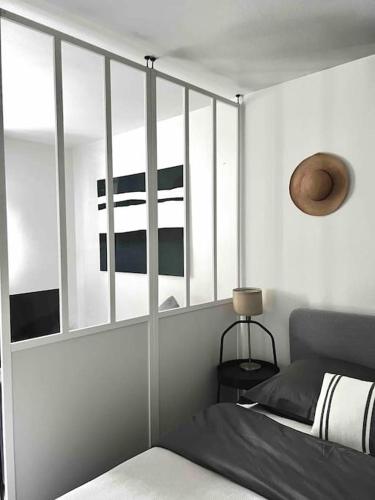 1 dormitorio con paredes blancas, 1 cama y espejo en Studio 30 m2 a 900 m du rer E, en Champigny-sur-Marne