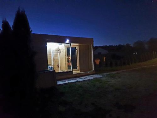 a small house with a window in a yard at night at Domek Jozef z prywatnym duzym Jacuzzi i sauna Przystan pod niebem in Leczyce