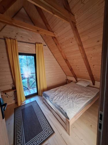 una camera da letto in una baita di tronchi con un letto e una finestra di Biały Domek II a Biszcza