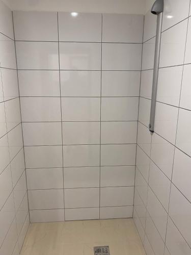 une douche avec des murs en carrelage blanc et un poteau dans l'établissement APPARTEL 76 CHAMBRES, à Rouxmesnil-Bouteilles