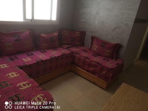 Appartement à louer wadie في فنيدك: أريكة في غرفة مع أوراق ووسائد وردية