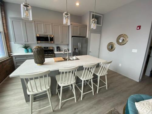 a kitchen with a island with chairs and a counter top at SWIZZLE Explore OTR and Downtown from Rhinegeist in Cincinnati