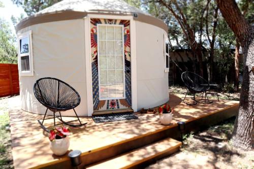 a tiny house with two chairs and a porch at Camposanto Glamping - The Macaw Yurt in Austin