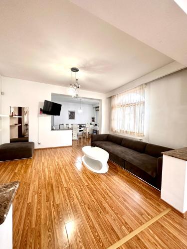 ein Wohnzimmer mit einem schwarzen Sofa und Holzböden in der Unterkunft Budapest Residence in Bukarest