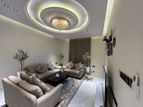 una sala de estar con sofás y una lámpara de araña. en شقة فاخرة غرفة وصالة بالعارض دخول ذاتي ١٠, en Riad