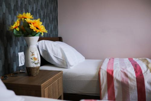 a bedroom with a bed and a vase with flowers on a table at Migro Lux sobe in Arilje