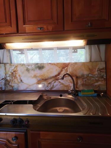 a kitchen with a sink and a counter top at camping hydraswave bungalow caravan in Thermisía