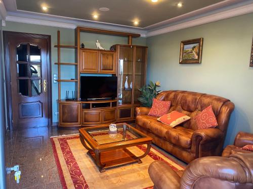 a living room with a leather couch and a coffee table at PRIMERA LINEA PLAYA AMERICA in Nigrán