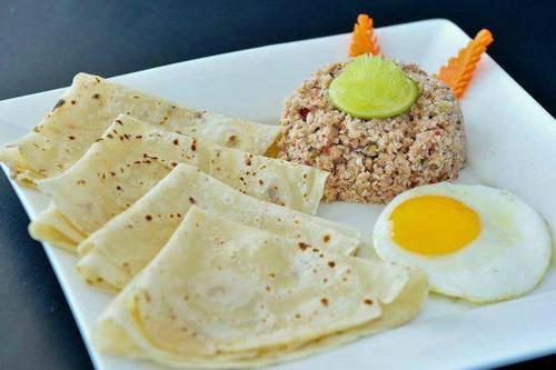 a white plate of food with an egg and crackers at The Bilimbi Guesthouse & Inn in Huraa