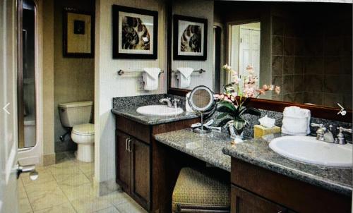 a bathroom with two sinks and a toilet and a mirror at Tahiti Village in Las Vegas