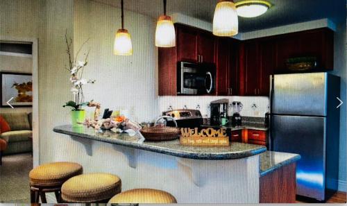a kitchen with a counter with chairs and a refrigerator at Tahiti Village in Las Vegas